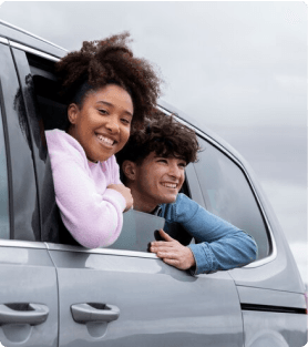 Crianças sorrindo apoiadas na janela de um carro